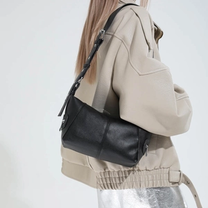 Detail of black pebbled faux leather shoulder bag with adjustable strap on female model