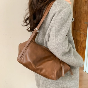 Detail view of brown leather tote bag with silver buckle and natural soft texture