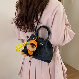 Detail einer dunkelgrauen Beuteltasche mit Gürtelschnalle und süßem Welpen-Plüschanhänger