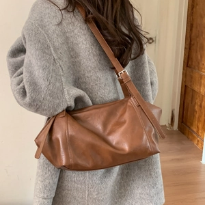 Detail view of a vintage brown leather shoulder bag with adjustable strap and silver buckle