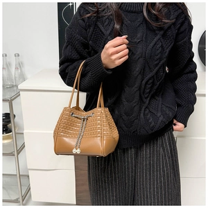Detail of a brown woven bucket bag with pearl drawstring and leather handles