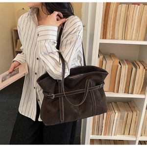 Detail view of deep brown tote bag with contrast stitching and adjustable buckle strap