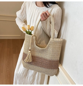 Detail of hand-woven straw tote with brown stripes and decorative tassel in resort setting