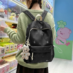 Side view of black nylon backpack with butterfly print and plush bear keychain