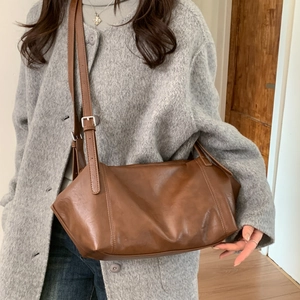 Detailed view of brown retro PU leather tote bag with adjustable strap on casual outfit