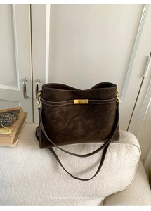 Détail du sac cabas en daim marron foncé avec coutures blanches et fermoir doré