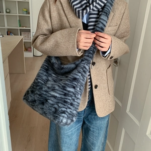 Close-up of grey and black striped faux fur shoulder bag with thick plush texture