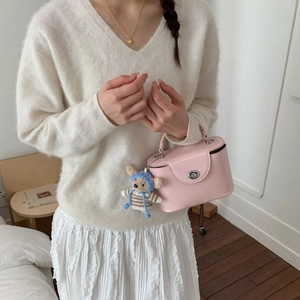 Detailed view of pink leather box bag with a cute teddy bear charm and silver lock