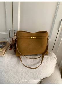 Détail du sac cabas en cuir marron avec fermoir doré rotatif et porte-clé ourson