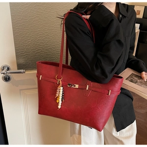 Close-up of a reddish-brown retro tote bag with vintage hardware and a beaded charm