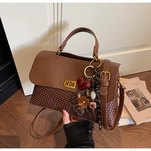 Detail of retro tote bag showing brown leather patchwork and woven texture with heart charm