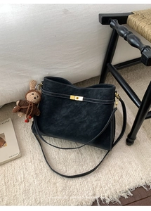 Détail du sac rétro noir avec surpiqûres blanches, serrure dorée et breloque lapin