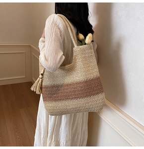 Detail showing the woven texture and tassel charm of a striped straw tote bag