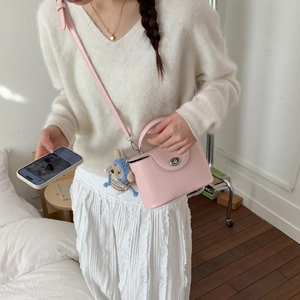 Detail of pink box crossbody bag with metal twist lock and cute blue bear plush charm