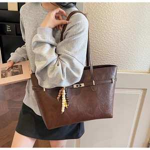 Detail shot of a dark brown faux leather tote bag with vintage texture and metal turn-lock