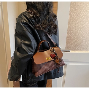 Detail of vintage brown tote with houndstooth texture and heart floral pendant