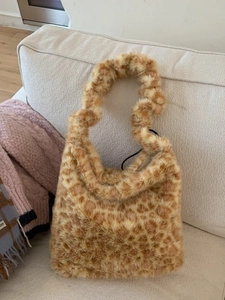 Fuzzy leopard print faux fur tote bag for women placed on a beige sofa in a cozy interior