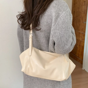Macro shot of a cream leather tote bag with soft pleats and adjustable silver buckle strap