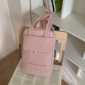 Pink quilted nylon handbag with multiple pockets and top handles shown on a wooden chair