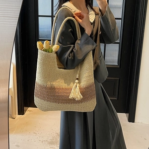 Handwoven straw tote bag with color-block design and tassels for beach vacations