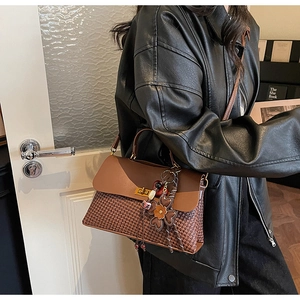Detail of vintage brown leather handbag with woven texture and gold metal twist lock