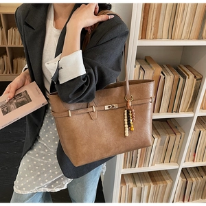 Detail of vintage brown leather tote bag with metallic turn-lock and beaded tassel