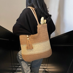 Striped straw tote bag with bohemian tassel and wooden beads shown on a model