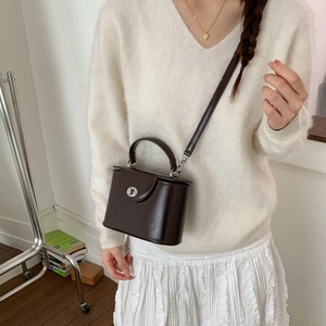 Detail view of dark brown vintage crossbody box bag with silver twist lock and top handle