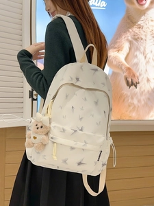 White nylon backpack with grey butterfly print and bear charm on a female model