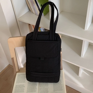 Macro shot of black quilted nylon crossbody bag with dual straps and large front flap pocket
