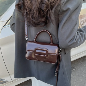 Detail view of the glossy dark brown mini square bag with polished finish and top handle