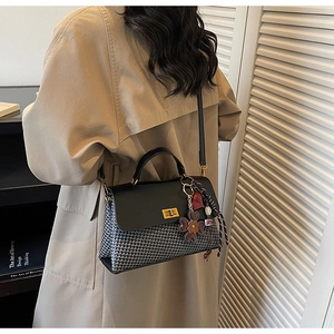 Detail of black and white houndstooth handbag with gold lock and floral charms