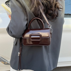 Detailed close-up of dark brown vintage faux leather handbag with tassel and buckle
