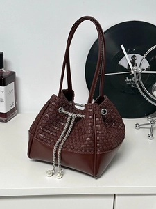 Burgundy woven bucket bag with drawstring closure and elegant pearl chain details