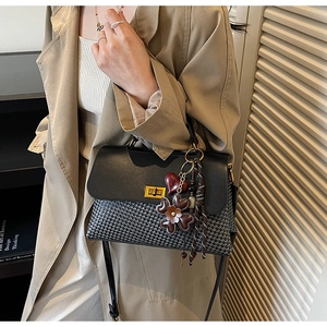 Close-up of black and white houndstooth handbag with metal lock and floral charms