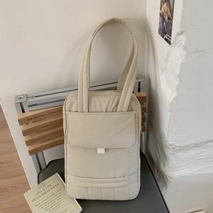 Detailed view of beige quilted nylon crossbody bag featuring large front flap pocket