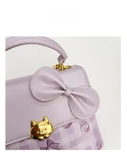 Detail of light purple leather handbag featuring a golden cat buckle and cat prints