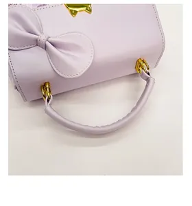 Detail of light purple bag featuring a gold cat clasp and leather bow decoration