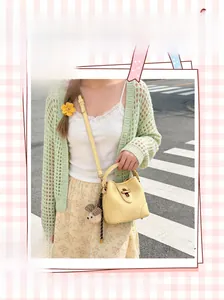 Detail view of yellow bucket bag with lychee texture, golden lock, and plush bear charm