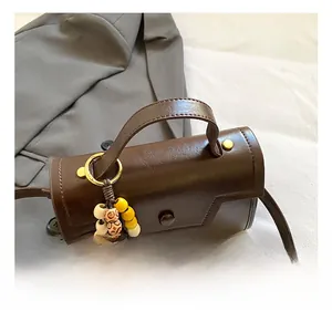 Détail d'un sac à main marron foncé avec poignée ronde et breloque en perles