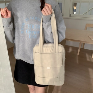 Minimalist beige crossbody bag shown on a model in a cozy, natural home setting