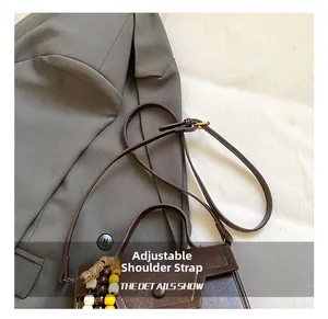 Détail de la bandoulière réglable et du pendentif à perles sur le sac à main marron