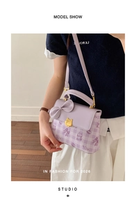 Detail view of lavender handbag with golden cat clasp and cute butterfly bow accent