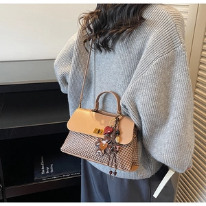 Detailed view of brown woven and leather handbag with vintage heart-shaped charms
