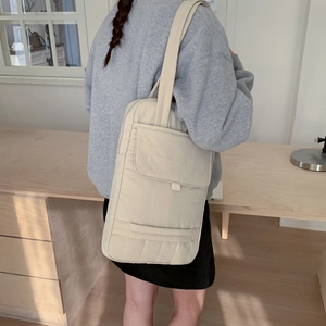 Close-up of minimalist cream vertical canvas tote bag with front flap pocket detail