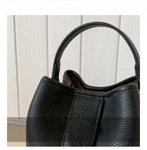Detail view of black litchi pattern bucket bag with wide handle and golden oval swivel lock