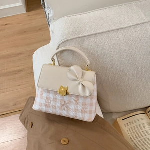 Detail of cream square handbag with gingham fabric, leather bow and gold cat-shaped clasp