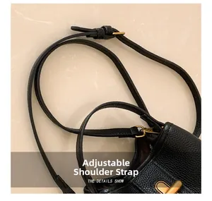 Detail of adjustable black pebble leather shoulder strap with gold metal buckle