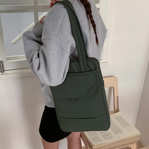 Detail of dark green nylon tote bag with front flap pocket and sturdy shoulder strap