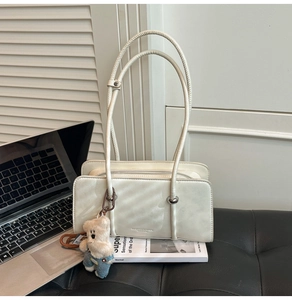 Detail of white minimalist faux leather shoulder bag with cute denim teddy bear charm
